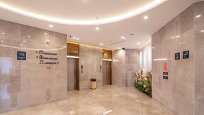 A modern lobby with marble flooring, a reception desk, and directional signs for amenities like a restaurant, bathroom, and elevator. - DALIAN xinghaiguangchang xianlu yaduo (Dalian City)