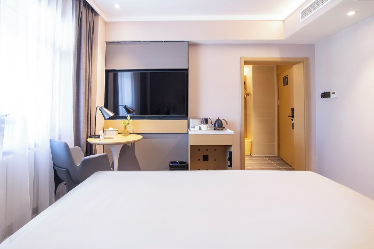 Ein Hotelzimmer mit Bett, Schreibtisch, Fernseher und Bad.
