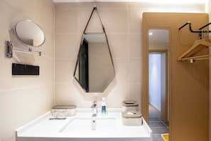 A modern bathroom with a white sink, a mirror, a towel dispenser, and a toilet paper holder. - DALIAN xinghaiguangchang xianlu yaduo (Dalian)