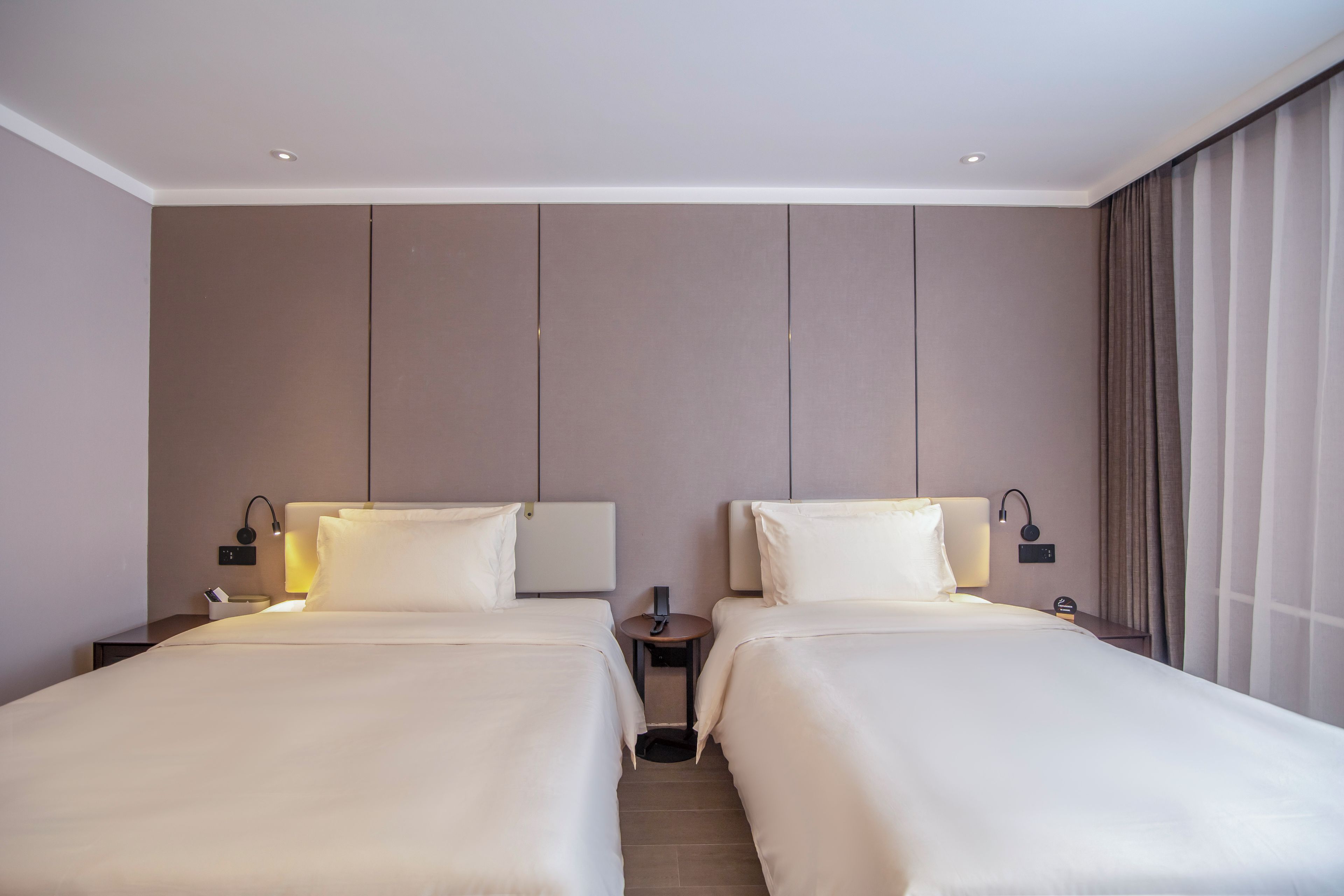 Une chambre d’hôtel avec deux lits, chacun étant équipé d’un oreiller et d’une table de chevet avec une lampe.