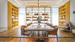 A spacious room with a large dining table surrounded by chairs, flanked by tall bookshelves filled with books and decorative items. - DALIAN xinghaiguangchang xianlu yaduo (Dalian City)