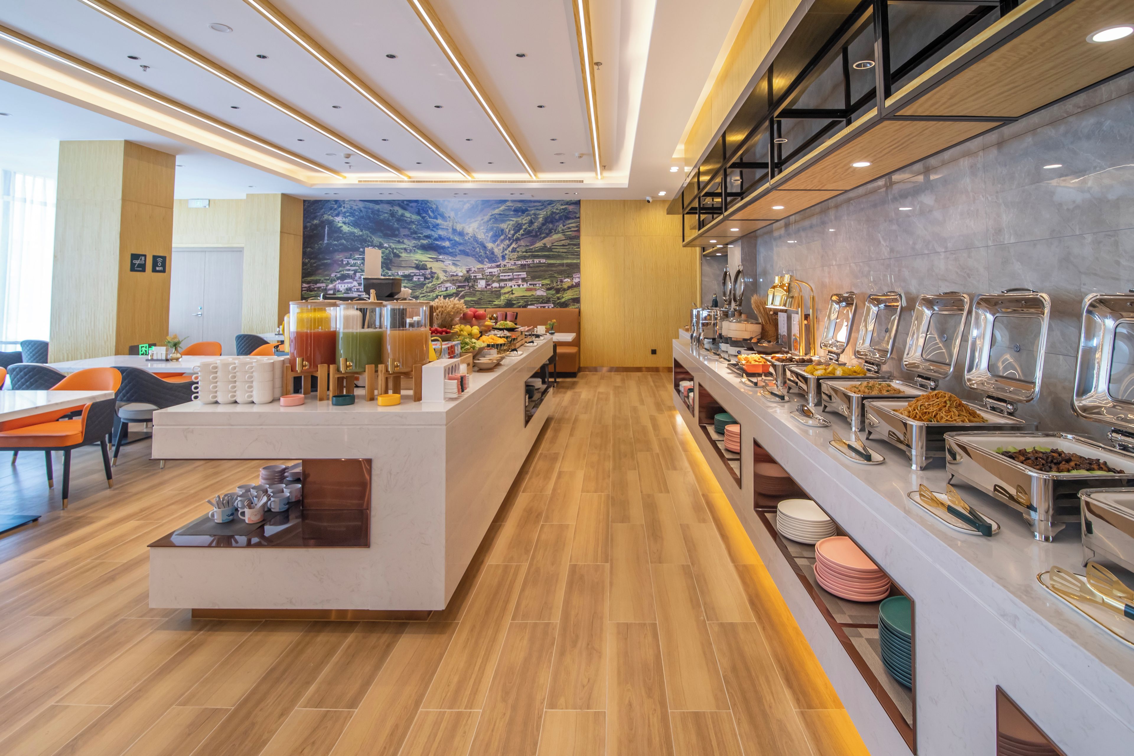 A modern hotel breakfast area with a buffet, seating, and a mural on the wall.