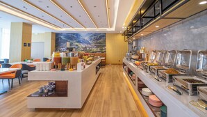 A modern hotel breakfast area with a buffet, seating, and a mural on the wall. - DALIAN xinghaiguangchang xianlu yaduo (Dalian City)