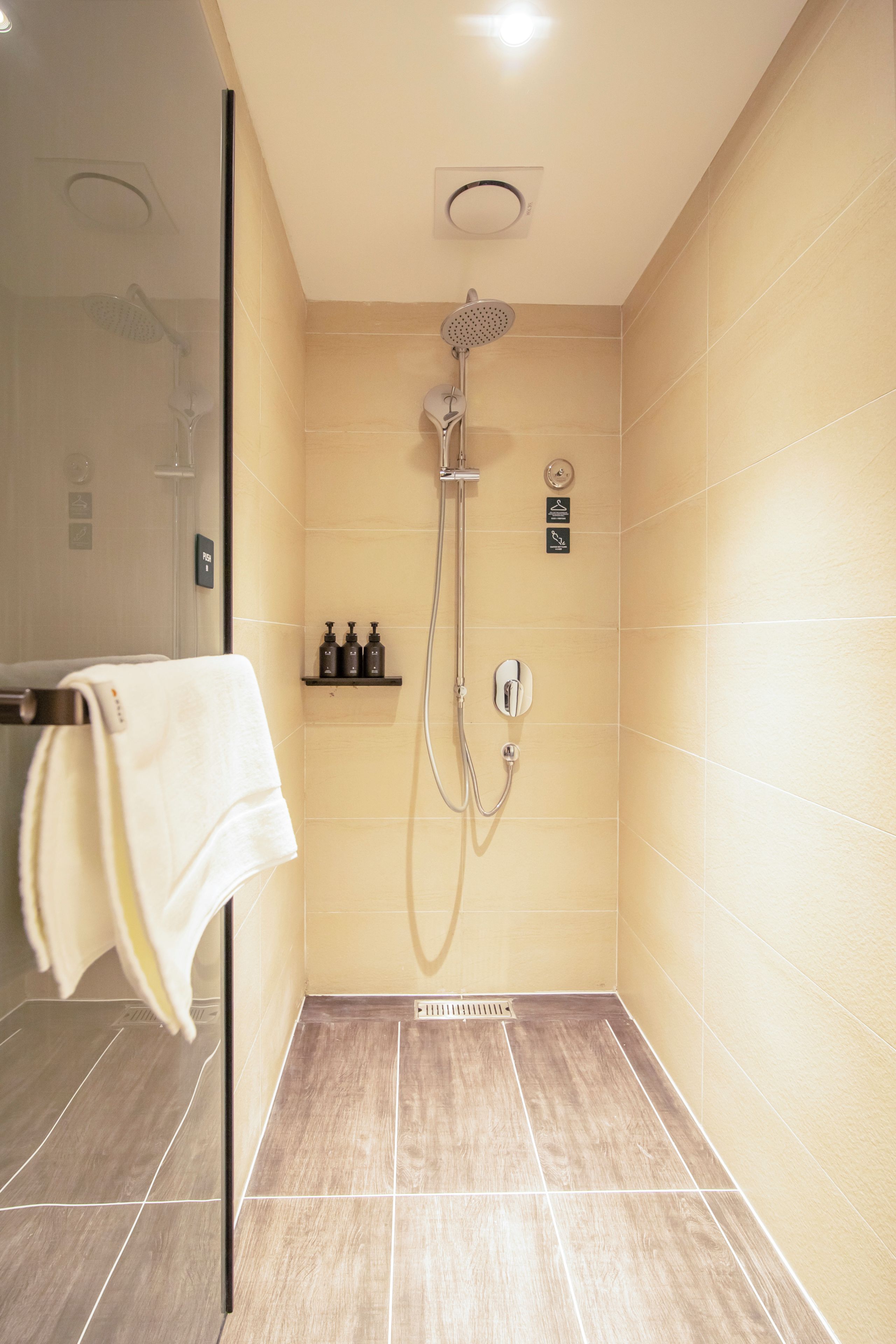 Un baño moderno con ducha, toallero y estante con artículos de aseo.