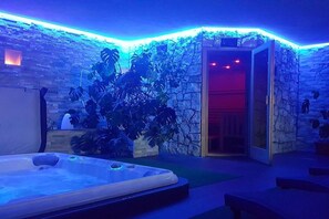 A spa area with a hot tub, stone walls, and tropical plants. - Holiday home with 1 bedroom (Steinhaus)