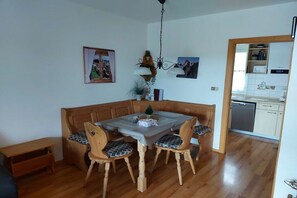 A dining area with a wooden table and chairs, a bench, and a chandelier. - Holiday home with 2 bedrooms (Lechbruck am See)