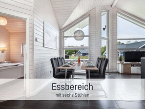 Comedor con una mesa dispuesta para seis, ventanas grandes y vistas al exterior.