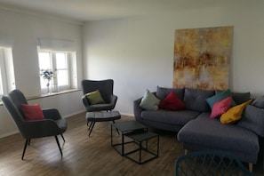 Una sala de estar con un sofá gris, un sillón negro y una mesita.