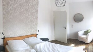 Une chambre à coucher avec un lit en bois, un miroir rond, une chaise et une porte.