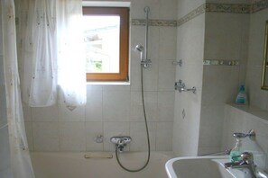 Un baño con bañera, ducha y ventana.