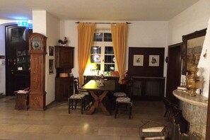 A dining area with a wooden table, chairs, a clock, and a window with curtains. - Holiday home in the Palatinate with 1 bedroom (Germersheim)