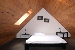 A bedroom with a sloped ceiling, a bed, a small bedside table, a lamp, and a picture frame on the wall. - Holiday apartment with 3 bedrooms (Crozon)