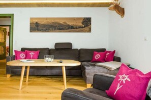 A living room with a sofa, a coffee table, and a painting on the wall. - Holiday apartment with 3 bedrooms (Garmisch-Partenkirchen)