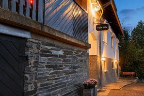 A building with a stone facade, a sign reading 'Villa Elvie,' and a pathway leading to a bench.