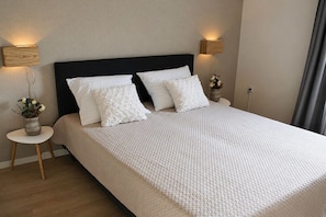 A neatly made bed with a black headboard, two bedside tables with lamps, and a vase with flowers on one table.