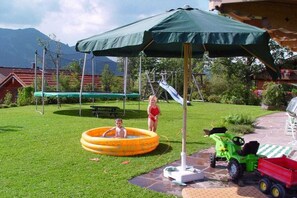 A backyard with a trampoline, a swing set, a slide, and a small inflatable pool. - Holiday apartment with 2 bedrooms (Lenggries)