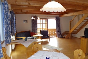 A wooden-floored living room with a sofa, a small table, and a staircase. - Holiday apartment with 2 bedrooms (Lenggries)