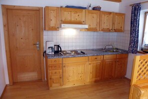 Uma cozinha com armários de madeira, bancada, cafeteira e pia.