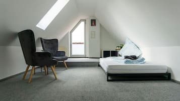 Una habitación pequeña y moderna con tragaluces, una cama, una silla y una mesita.