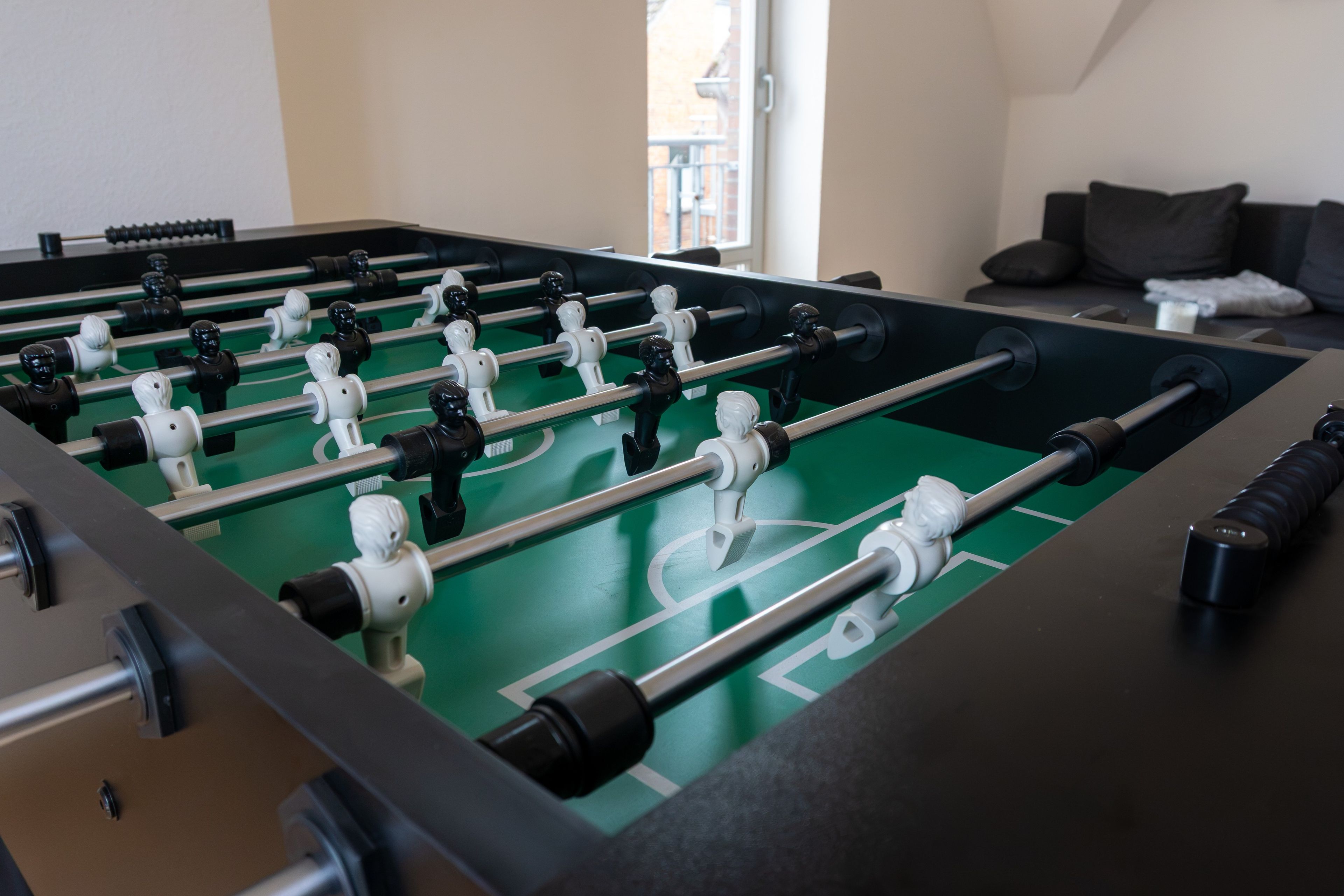 Ein Kicker mit einer grünen Spielfläche und schwarz-weißen Spielerfiguren.