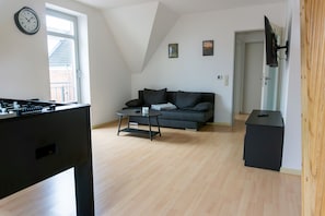 Ein modernes Wohnzimmer mit einer Couch, einem Couchtisch und einem Kicker.