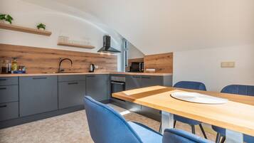 Eine moderne Küche mit grauen Schränken, einer Holz Arbeitsplatte und einem Essbereich mit Tisch und Stühlen.