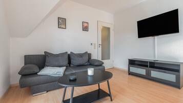 A modern living room with a grey sofa, a coffee table, and a TV mounted on the wall.