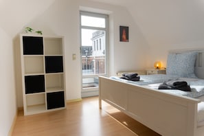 Ein Schlafzimmer mit einem Bett, einem weißen Kleiderschrank, einem Fenster, einem Nachttisch und einem Bild an der Wand.
