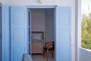 Una habitación con una cama, una silla y una puerta que da a un espacio exterior.