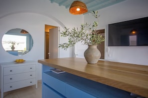 Een moderne keuken met een houten aanrecht, een vaas met planten, een ronde spiegel en een aan de muur bevestigde televisie.