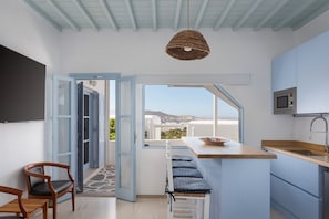 A modern kitchen with a large window, a hanging light fixture, and a bar area.