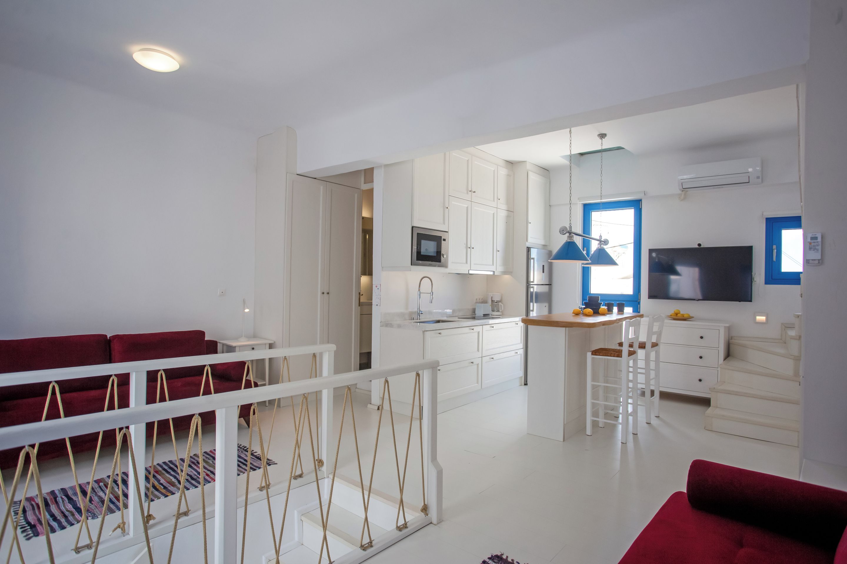 Eine moderne Küche mit weißen Schränken, einer zentralen Kücheninsel und einem Essbereich mit roten Sofas.