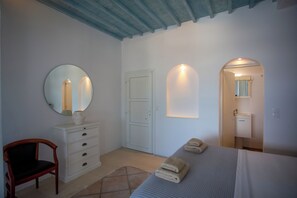 A bedroom with a bed, a dresser, a chair, and a mirror.