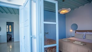 Ett sovrum med en säng, ett sängbord, en lampa och utsikt över hallen.