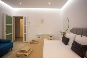 A modern bedroom with a bed, a desk, a chair, and a blue sofa.