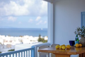 Una mesa de madera con limones y una botella en un balcón con vistas a la costa.