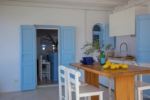 A kitchen with a wooden table, chairs, and a counter with a sink.