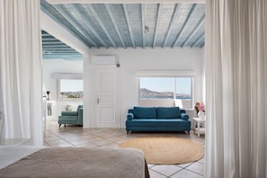 A room with a blue sofa, a white door, and a view of the sea.