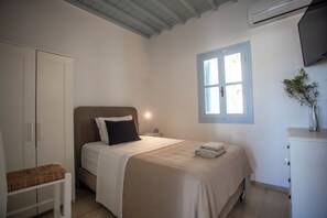 Een slaapkamer met een bed, nachtkastje, kledingkast en een raam.