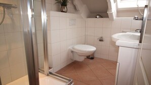 Een badkamer met douche, toilet en wastafel.