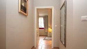 Un pasillo con piso de baldosas, un cuadro en la pared y un espejo.