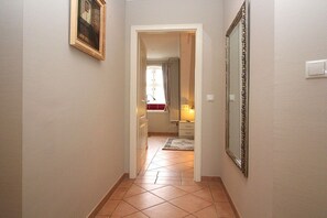 A hallway with a tiled floor, a framed picture on the wall, and a mirror. - Holiday apartment in Sylt with 4 bedrooms (Sylt \/ OT Westerland)