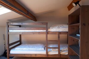 Ein Etagenbett mit Holzrahmen und ein Regalelement daneben.