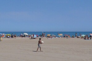 Ein Strand mit Menschen, Sonnenschirmen und blauem Himmel.