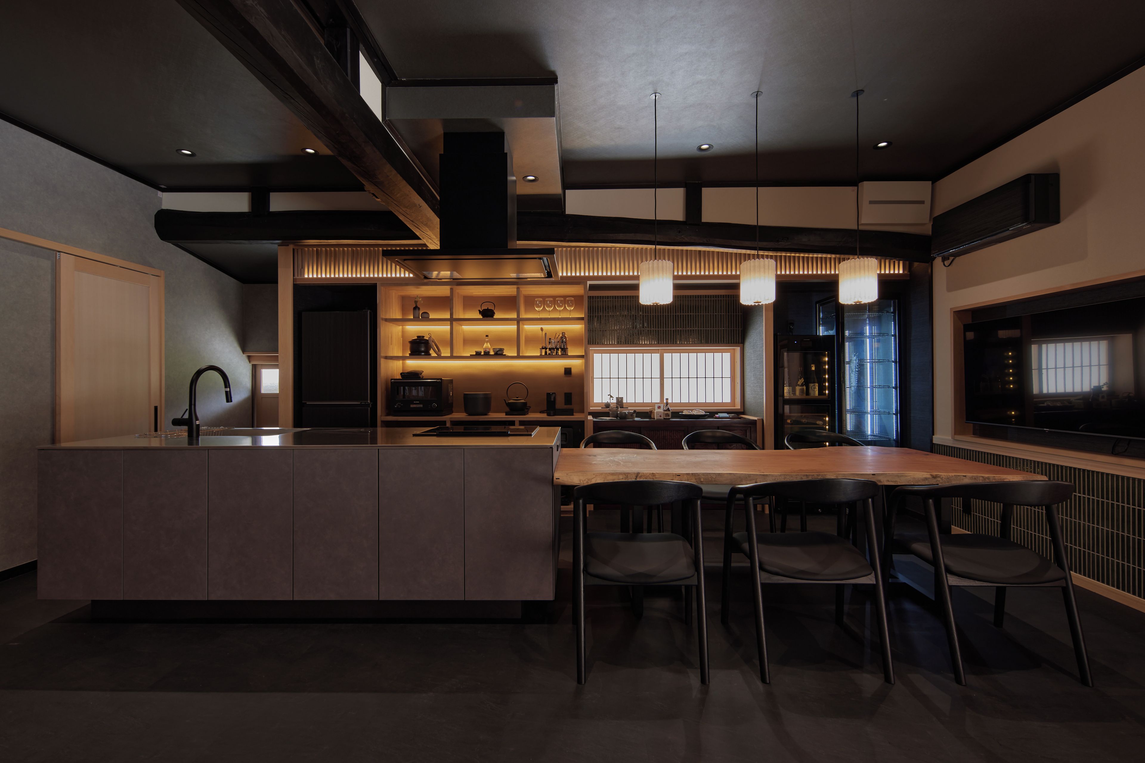 A modern kitchen with a central island, bar stools, and pendant lighting.