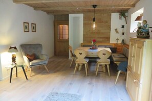 Ein Essbereich mit Holztisch und Stühlen, einer Lampe und einer Statue an der Wand.