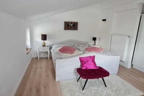 Ein Schlafzimmer mit einem Bett, Nachttischen, einem kleinen Hocker und einem Heizkörper.