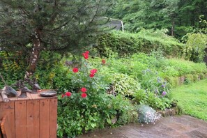 A garden with a wooden bench, a variety of plants, and a tree. - Holiday home with 2 bedrooms (Berchtesgaden)