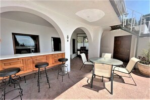 An outdoor patio with a bar, seating, and a view of the interior. - Holiday home in Roses with swimming pool (Roses)