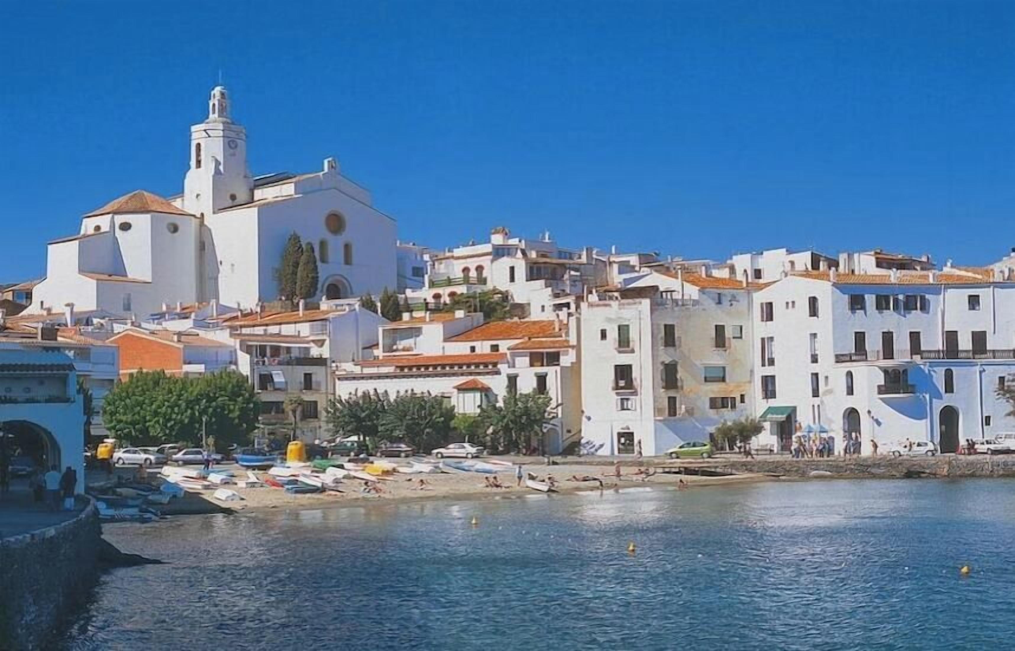 A coastal town with a prominent church, white buildings, and a beach area.